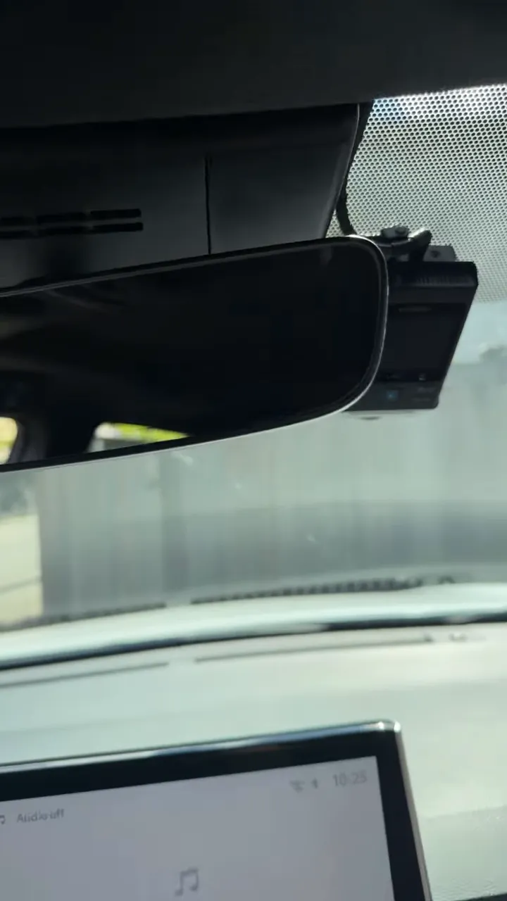 Front dash camera mounted beside the rearview mirror on the windshield