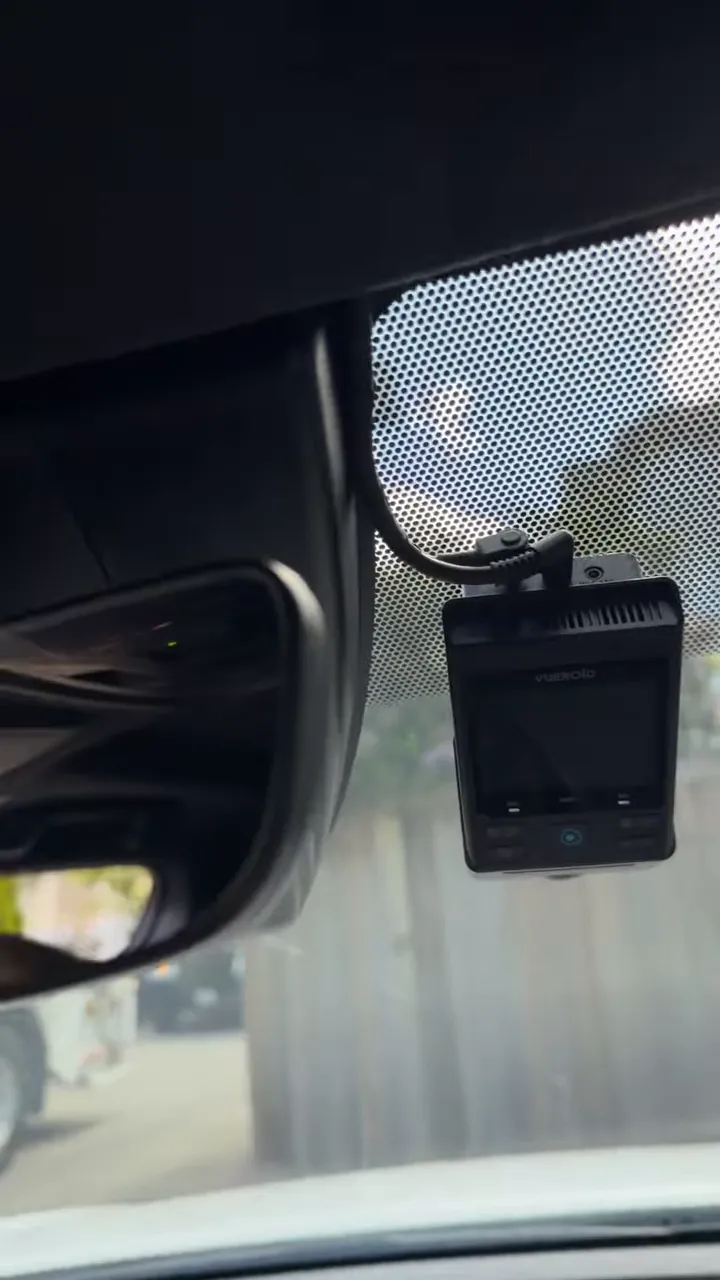 Front dash camera with power cable routed upward into the headliner near the mirror