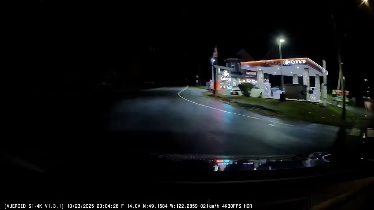 Gas station sign and pricing visible under night lighting