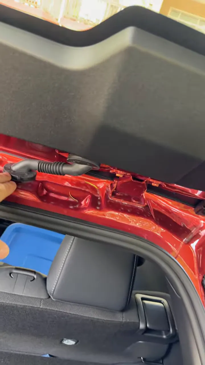 Rear hatch wiring boot with hand pointing at the rubber pass-through area