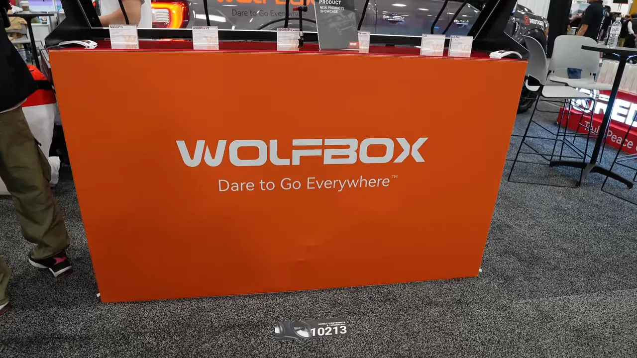 Orange Wolfbox exhibit counter with large Wolfbox logo and slogan 'Dare to Go Everywhere' at a tradeshow booth.
