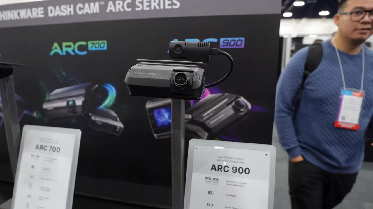 Clear frontal shot of a Thinkware ARC/ARK demo unit mounted on a stand with the ARC 900 product placard visible below and branded backdrop behind.