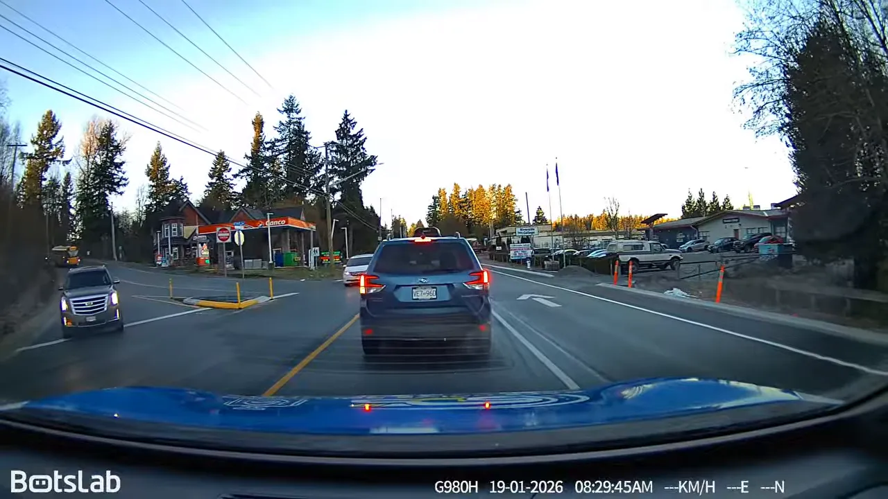Daytime dash cam footage stopped behind a dark SUV at an intersection