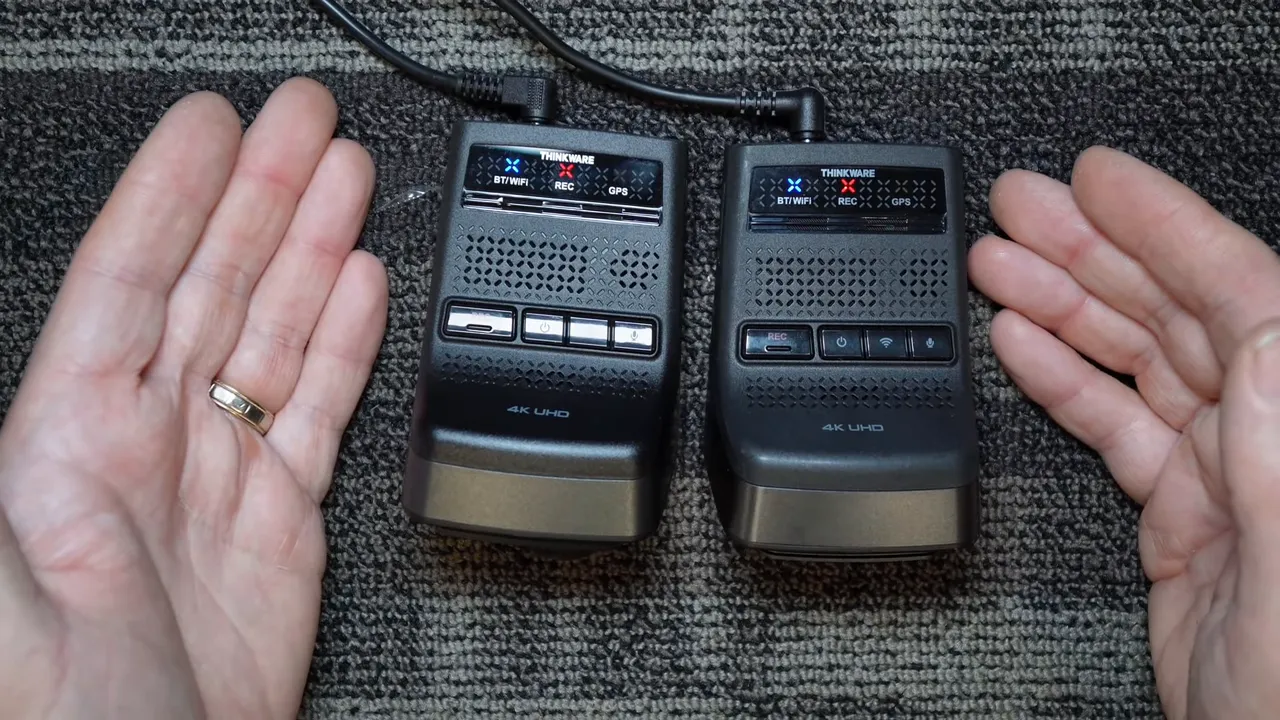 Two Thinkware 4K UHD dash cam modules side by side with status LEDs and hands framing them