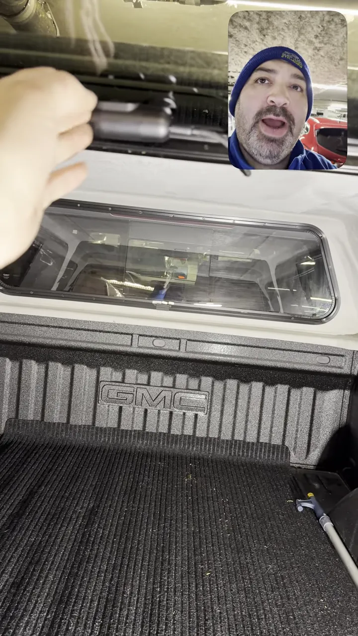 Rear camera mounted on canopy interior above the rear window with wiring visible and the GMC truck bed below.