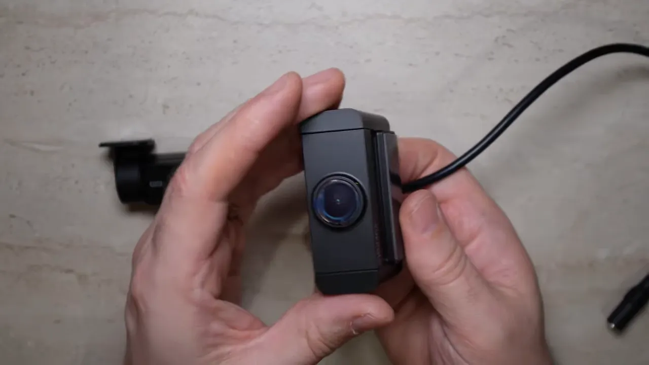 Front view of Vueroid rear camera held in hands showing lens and attached cable