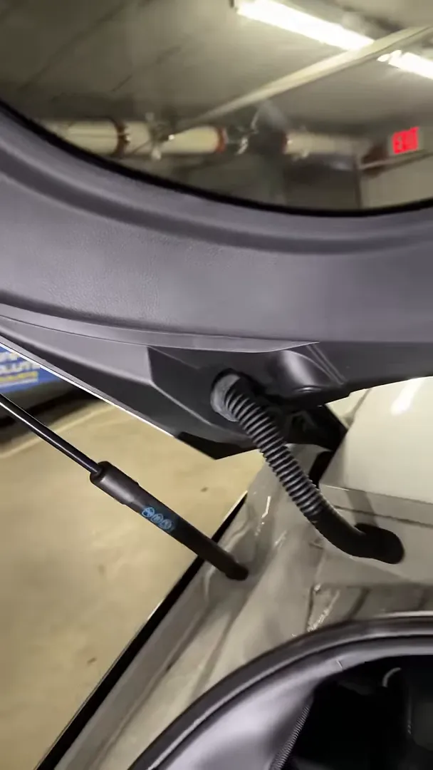 Rear hatch interior showing hydraulic strut, corrugated cable boot and window edge