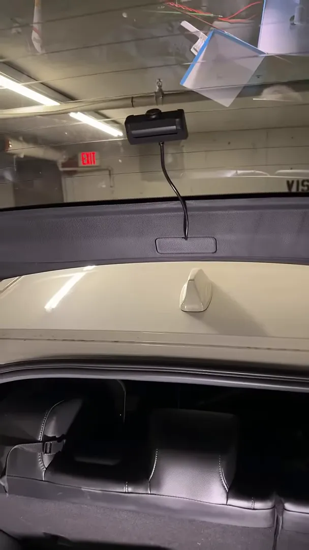 rear dashcam mounted on hatch glass with cable hanging into trunk, clear view