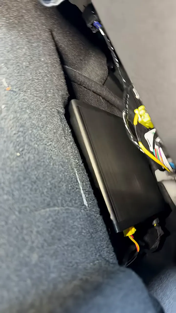 Black battery pack and bundled wiring positioned beneath a vehicle seat
