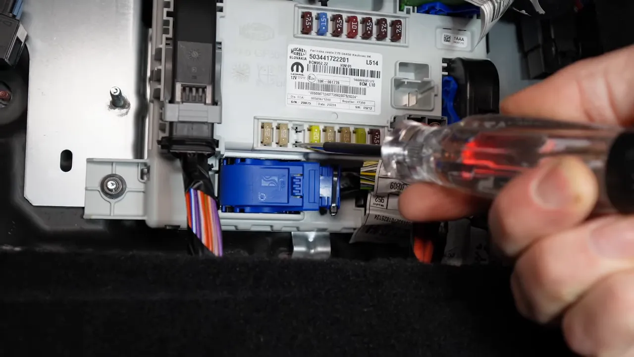 Tester with lit indicator probing a fuse in Giulia fuse panel