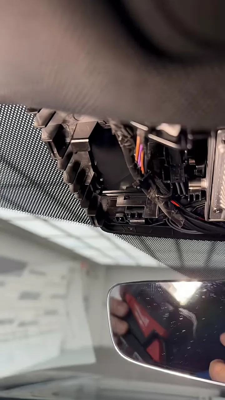 Opened rearview mirror trim showing factory wiring and cable routing space
