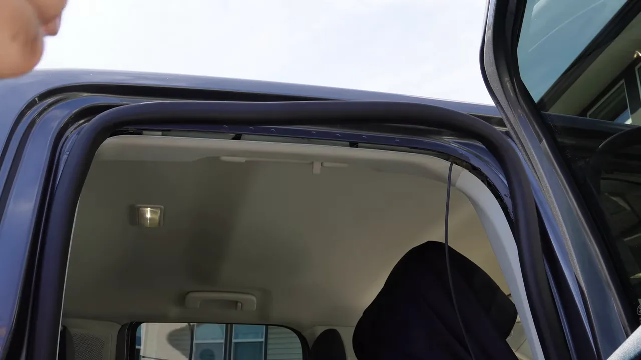 Hands showing the space behind the side curtain airbag near the roofline