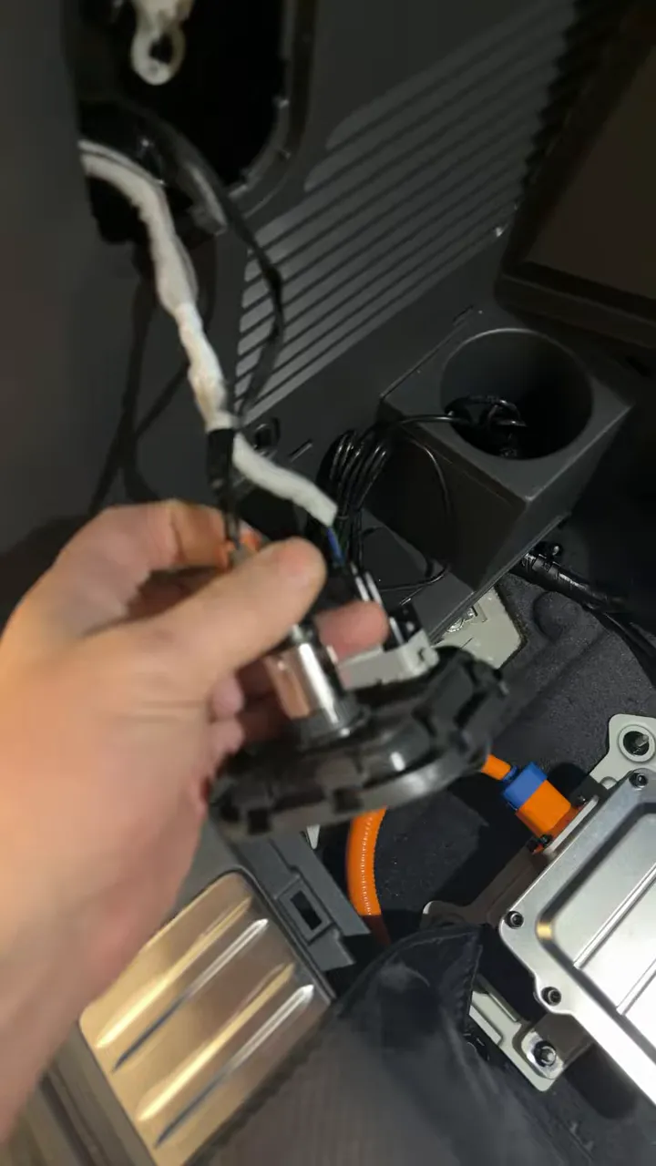 Removed cigarette lighter socket with wiring harness visible in the Kia EV9 rear storage showing accessory wires