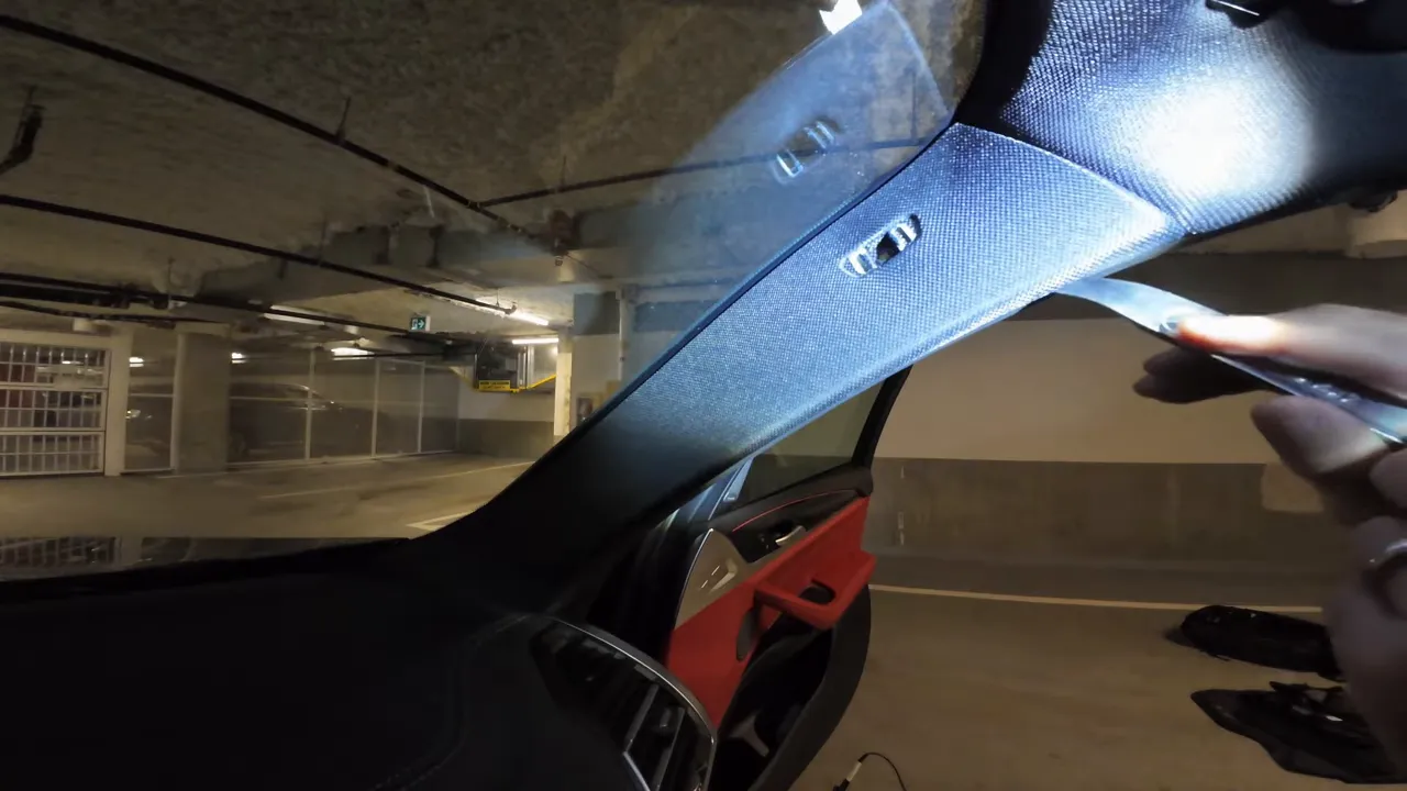 Trim tool prying A-pillar trim to access airbag area and route camera cable