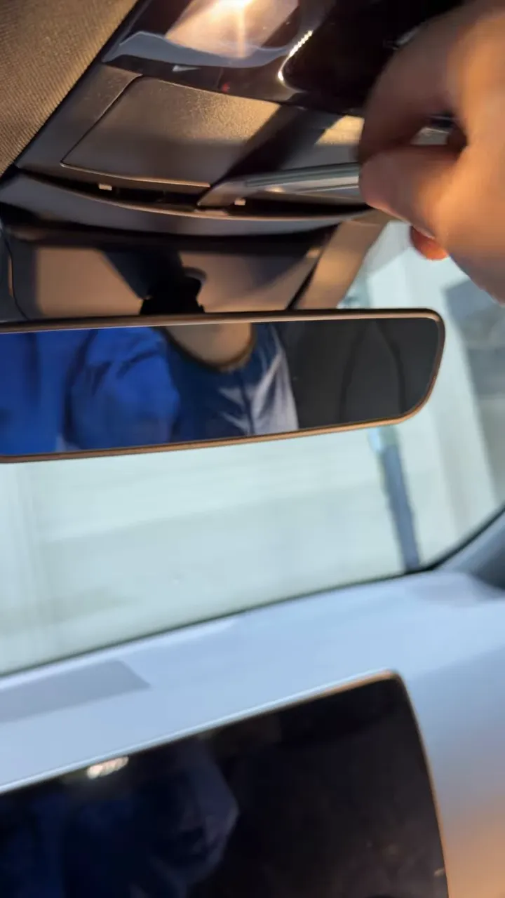 Close‑up of a trim tool lifting the center trim above the rear‑view mirror on a Lexus NX.