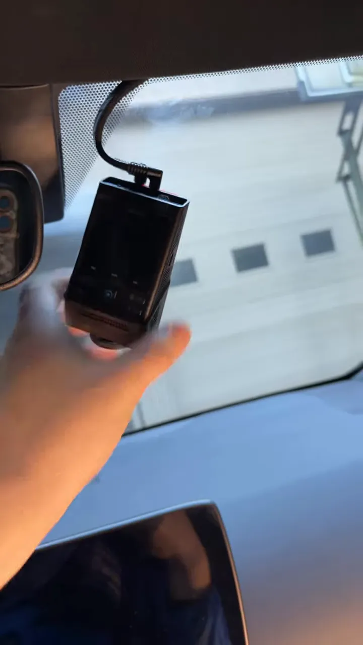 Dash camera mounted to the windshield on the passenger side of the rear view mirror with its power cable routed into the headliner trim.