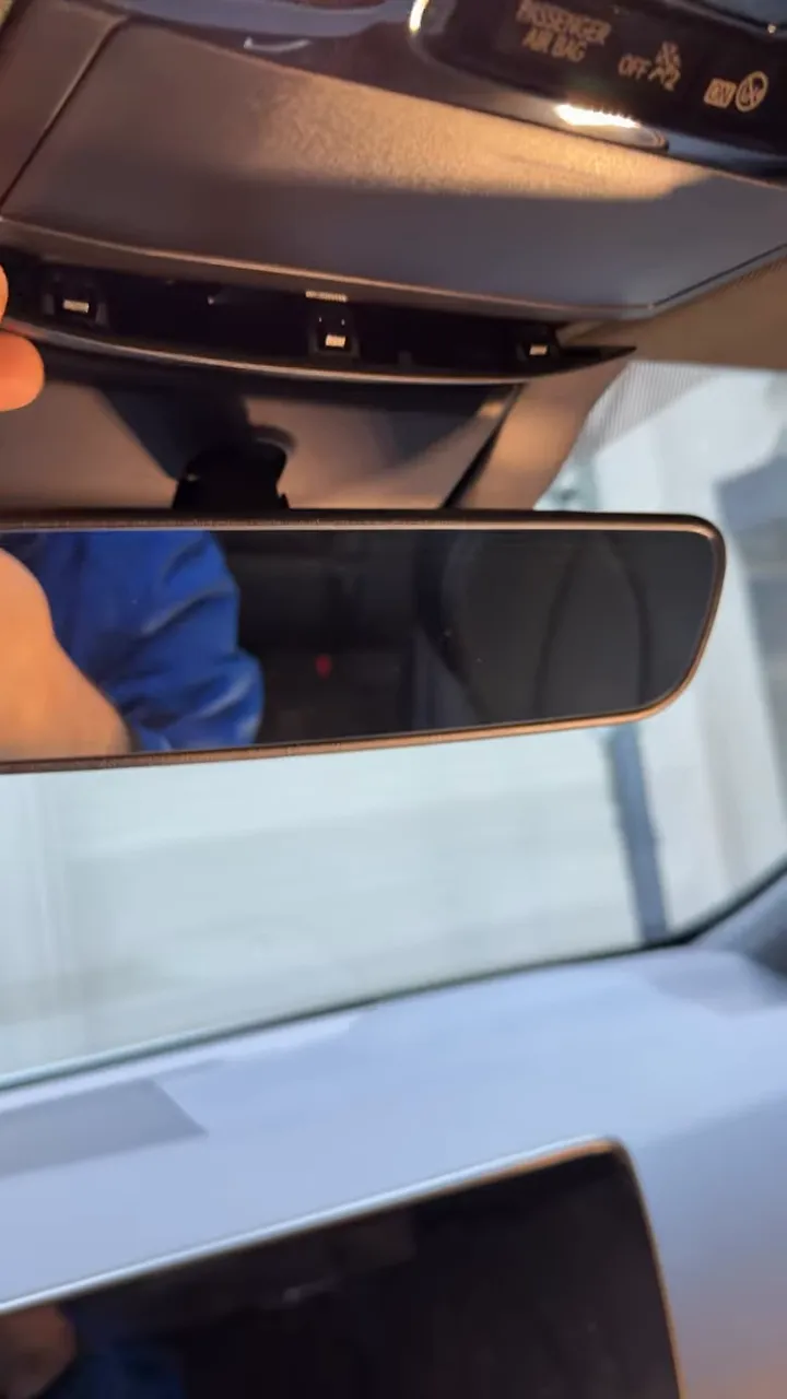 Lower edge of center trim pulled away showing plastic clips above the rear view mirror