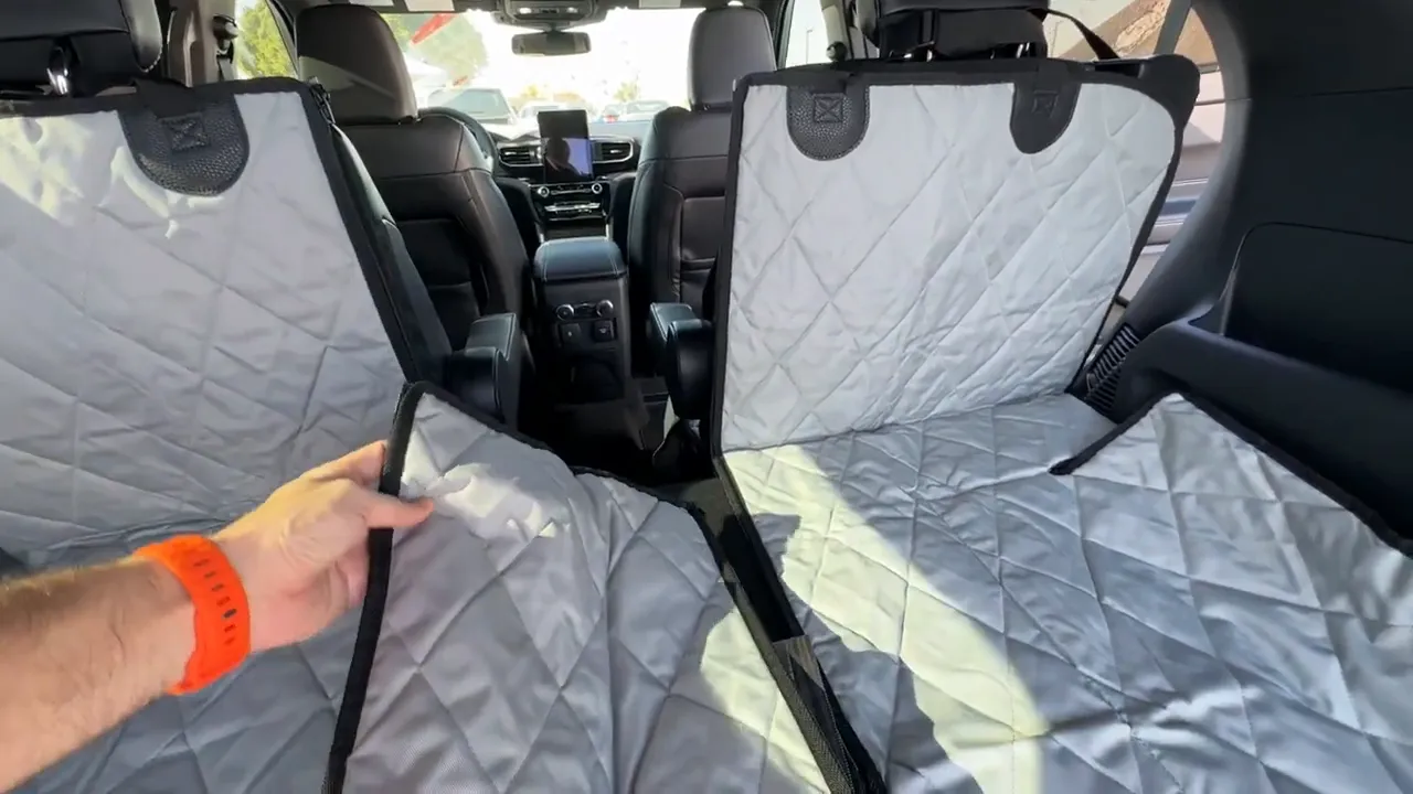 Hand lifting the center panel of the gray split cargo liner between two rear seatbacks