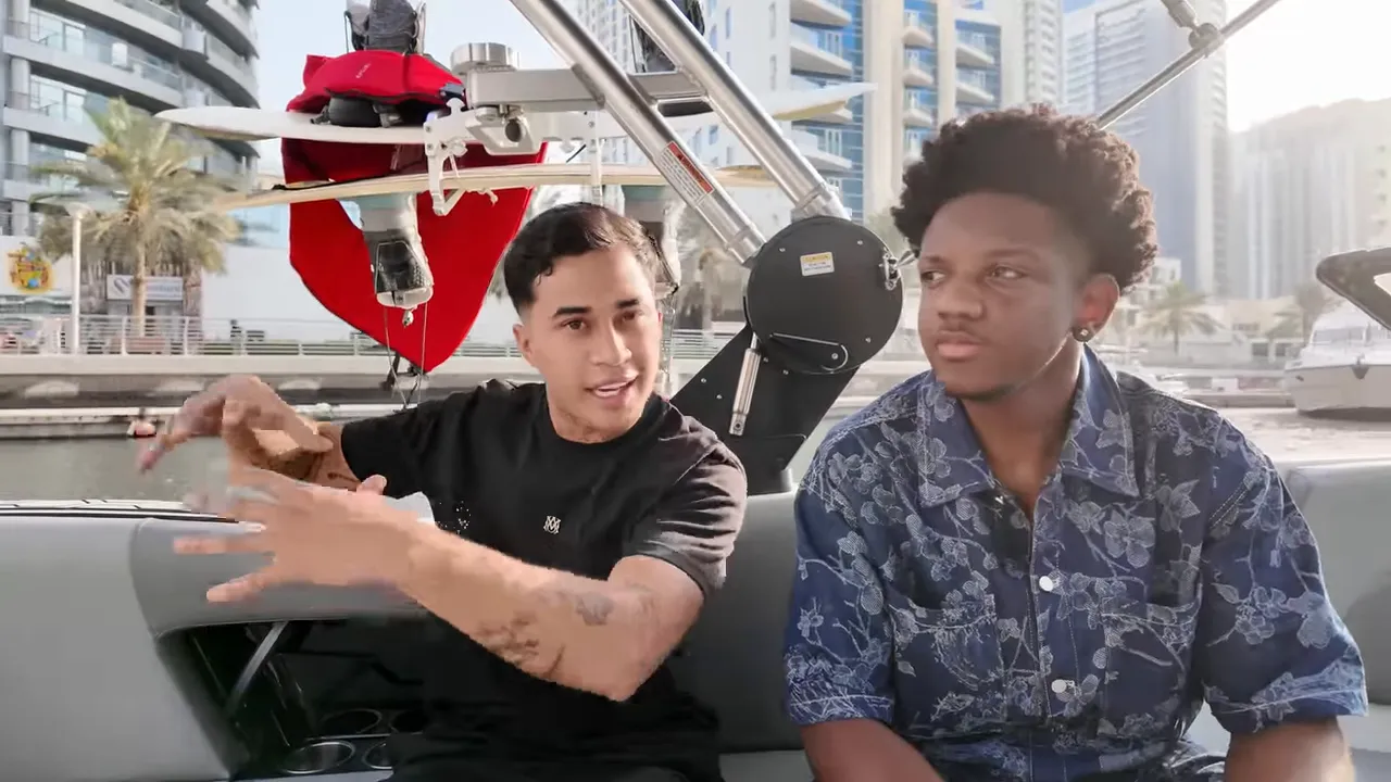 Deux hommes assis sur un bateau à Dubaï, l'un gesticule vivement pendant qu'on voit la planche de wake derrière et la marina en arrière-plan.