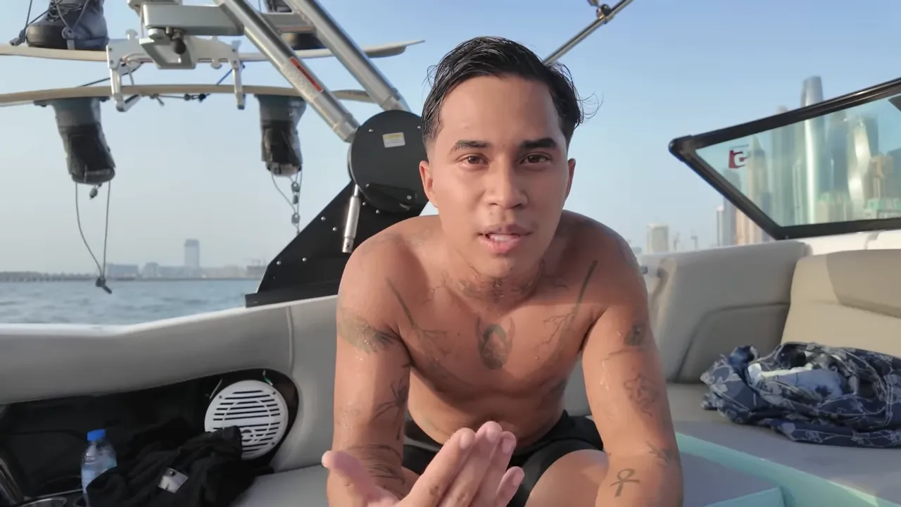 Personne torse nu gesticulant en parlant à bord d'un bateau avec la skyline de Dubaï en arrière-plan