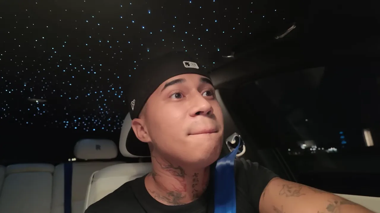 Jeune homme en casquette dans l'habitacle d'une voiture de luxe la nuit, regard réfléchi, plafond étoilé visible