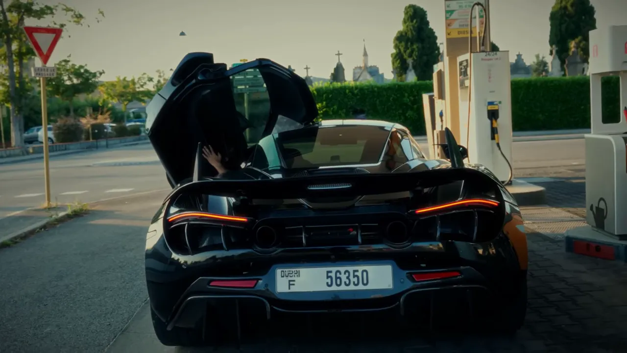 supercar noire vue arrière avec portes papillon ouvertes à une station-service, prise au niveau de la pompe