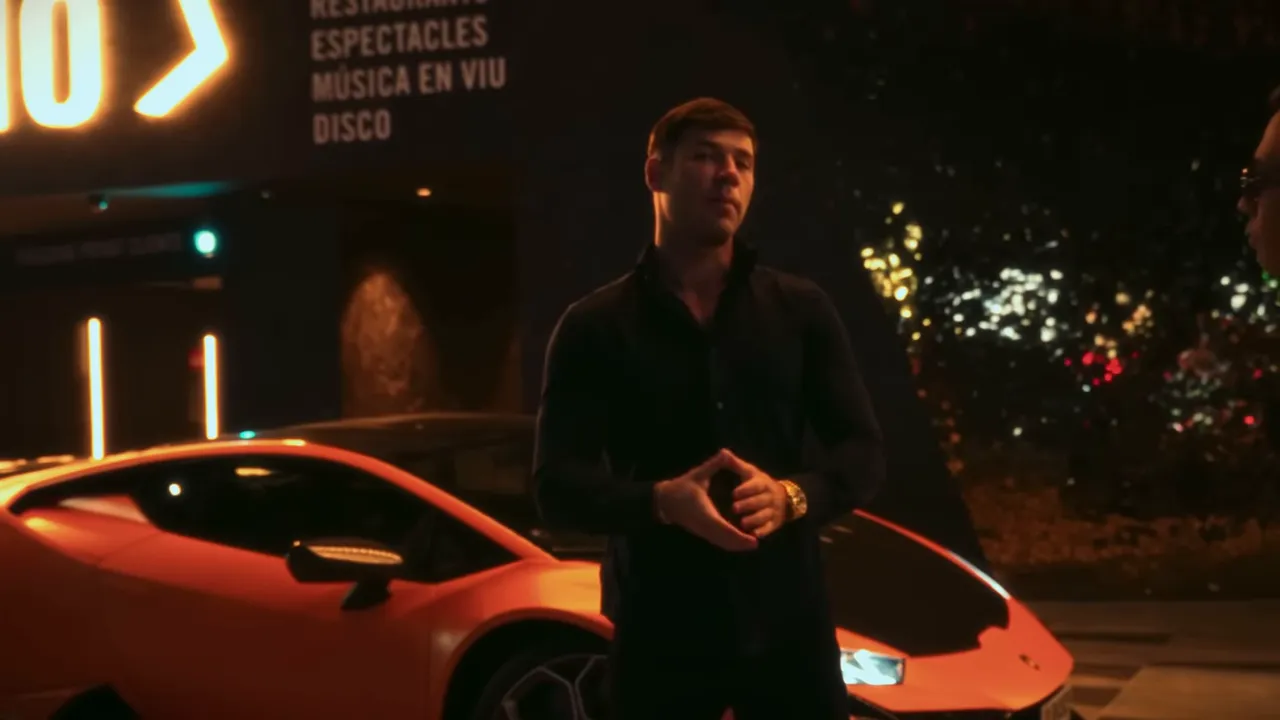 Homme debout devant une Lamborghini orange garée à l'entrée d'un casino illuminé, panneau indiquant restaurants et disco visible