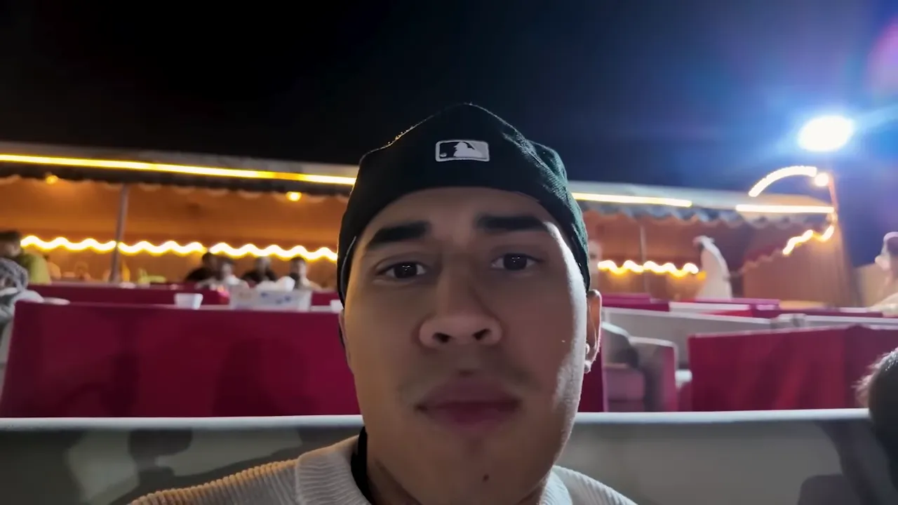 Portrait selfie d'un homme portant une casquette dans un espace événementiel éclairé, regardant la caméra.
