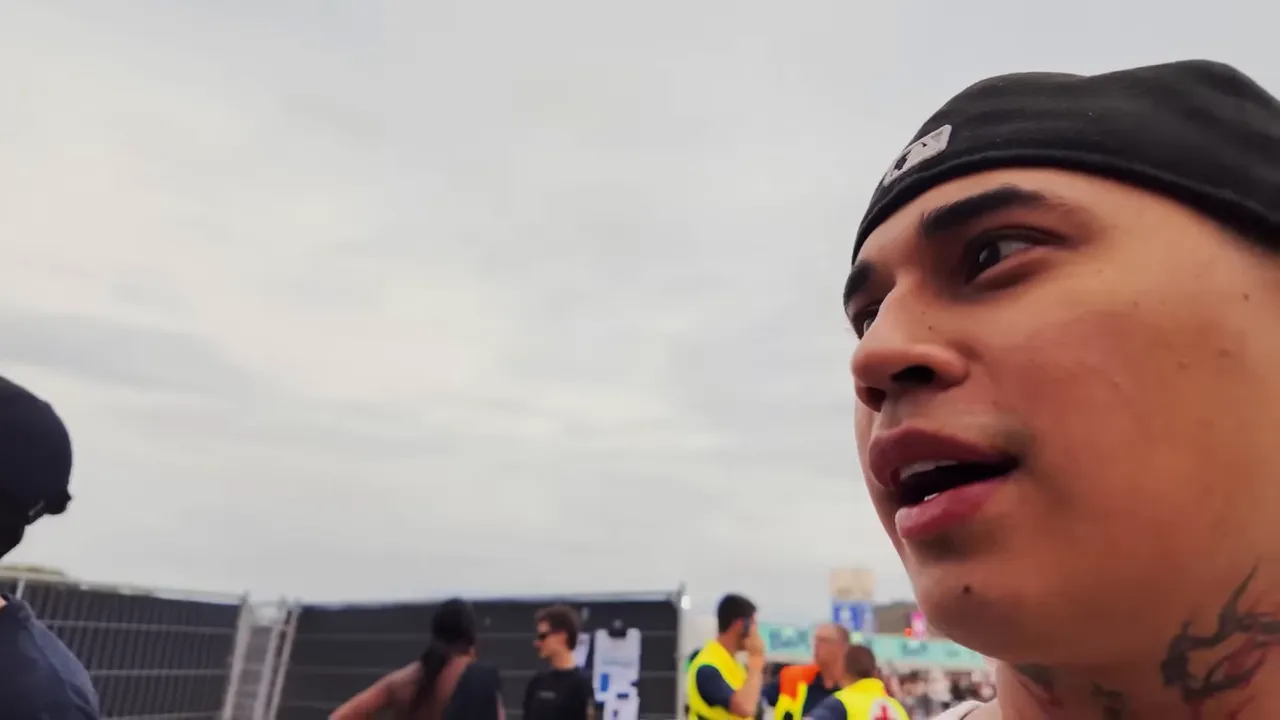 Scène de festival avec foule et équipe de sécurité, vlogueur enregistrant un micro-moment