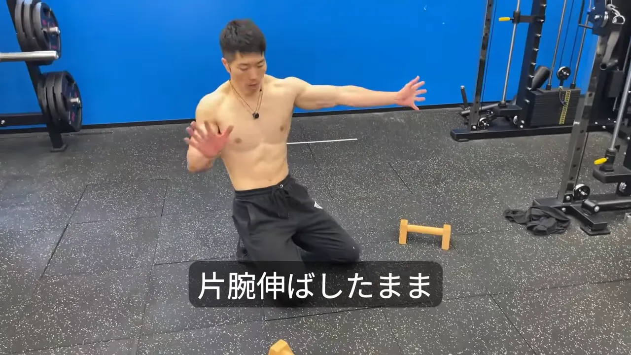 片腕を伸ばしたままアーチャープッシュアップの形を見せるトレーナー