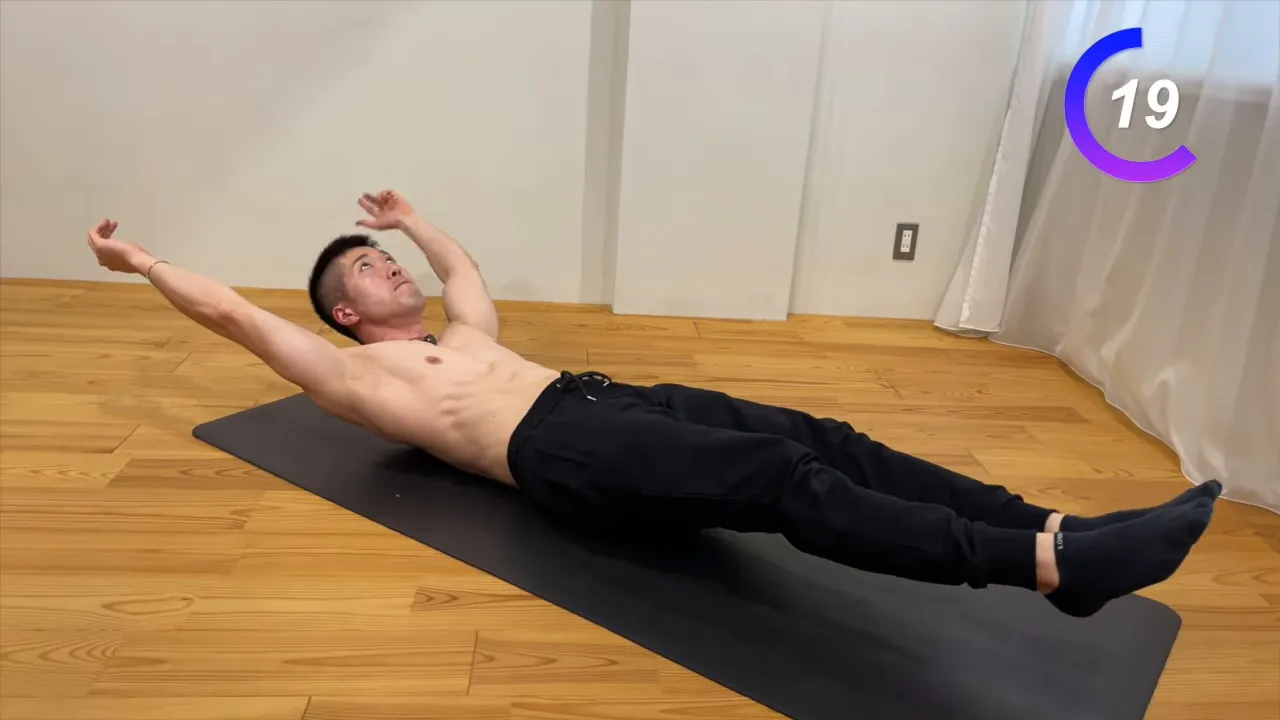 床で腕と脚を伸ばしてホローボディを保持する姿勢