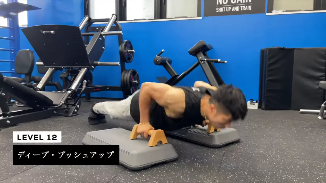 両手のプッシュアップバーを台の上に置いて深く沈むディーププッシュアップをする男性