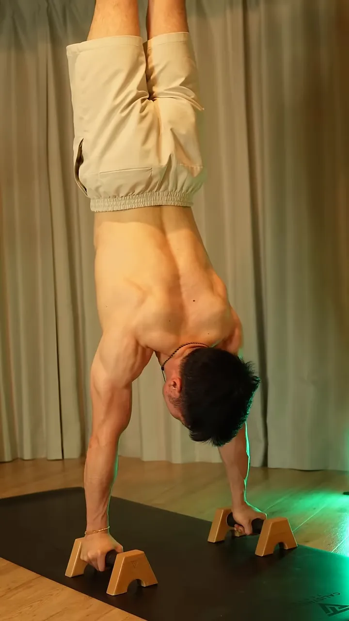 二つのバーを握り、腕と脚を伸ばして倒立している姿勢