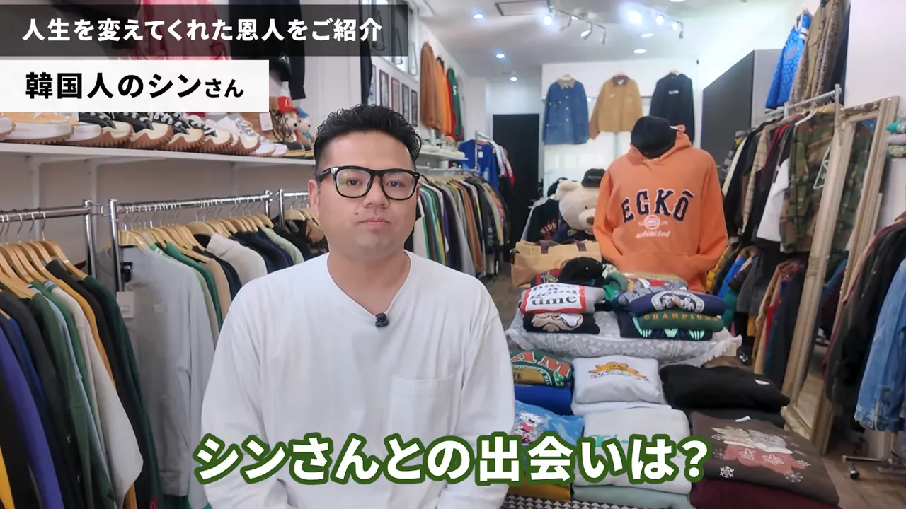 古着店の中で話す人物と手前に並ぶ折りたたまれた古着、左右にラックがある店舗風景