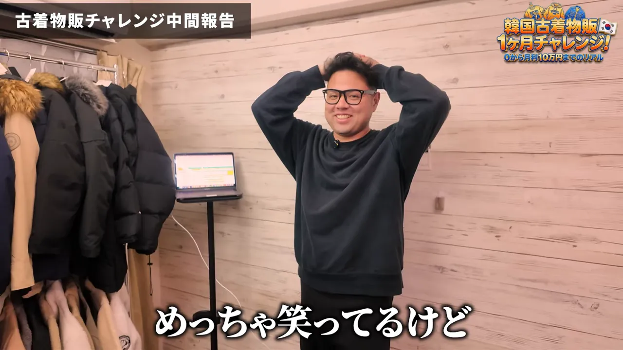 ハンガーラックに掛かった古着とノートPC、リラックスした表情の話者が写る作業スペース