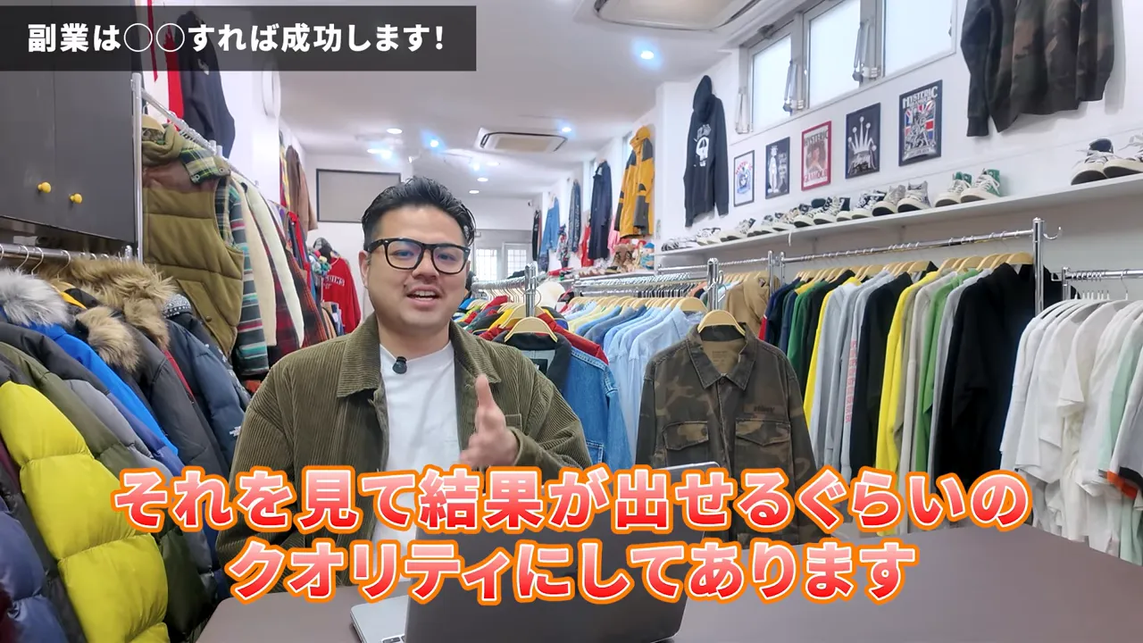 韓国古着店でノートPCを前に話す男性とラックに並ぶジャケットやTシャツ