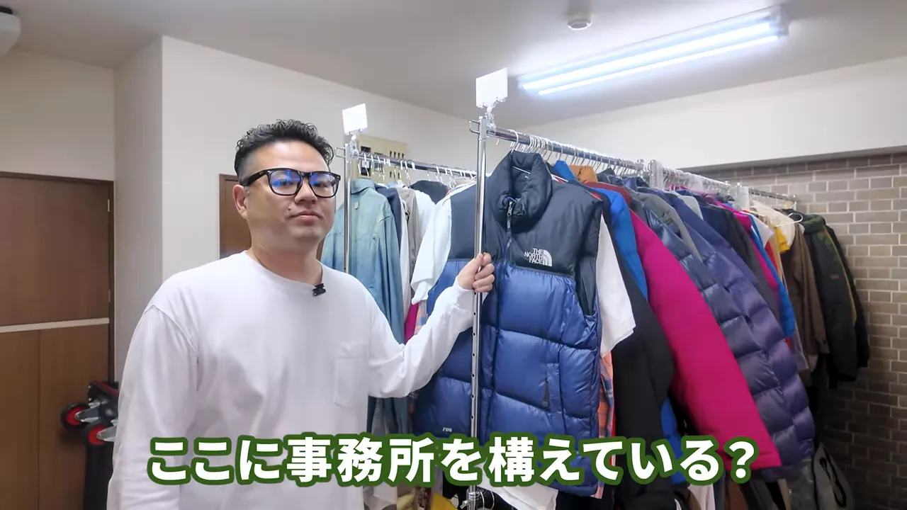 衣類ラックが並ぶ保管事務所の内部とスタッフが指し示す光景