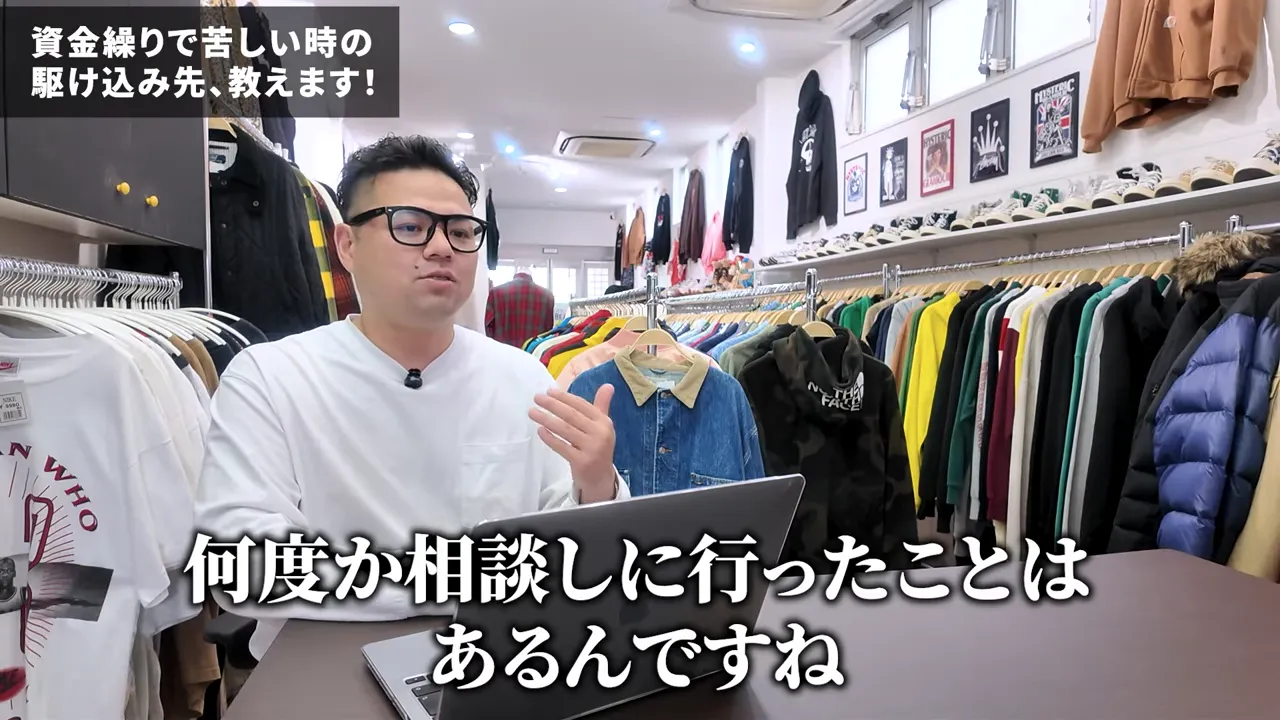 店舗内でノートPCの前に座り『何度か相談しに行ったことがある』と話す男性のショット