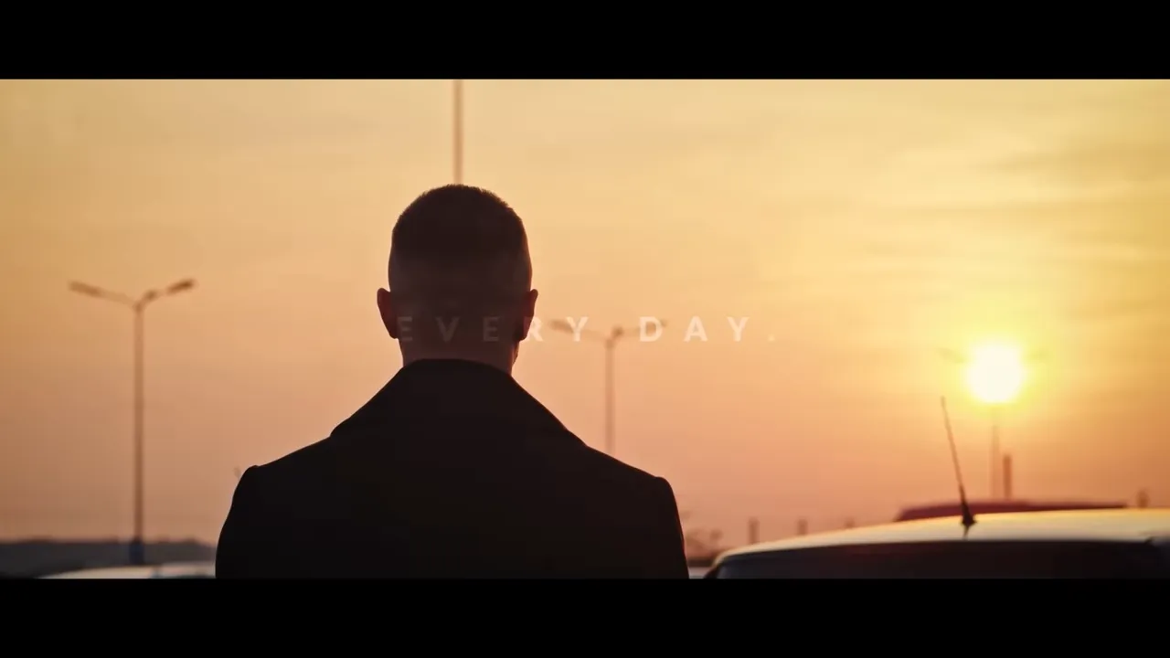 persona di spalle che guarda l'alba in un parcheggio, testo sfocato 'everyday'