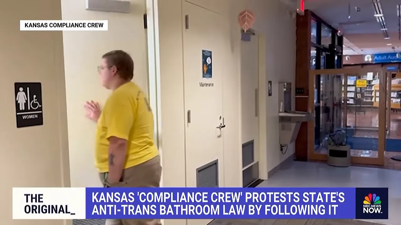 A person in a yellow shirt entering a restroom beside a women’s and wheelchair-accessibility sign