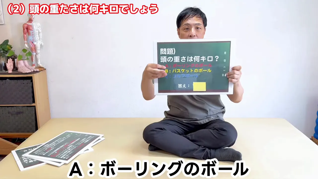 緑色のボードに頭の重さクイズの選択肢が表示されている