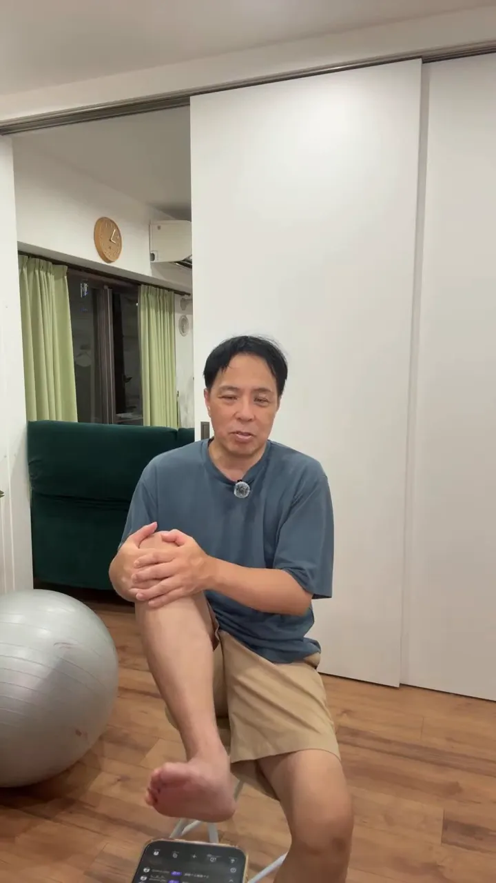 椅子に座り、片膝を両手で支えて足を床から持ち上げている姿勢