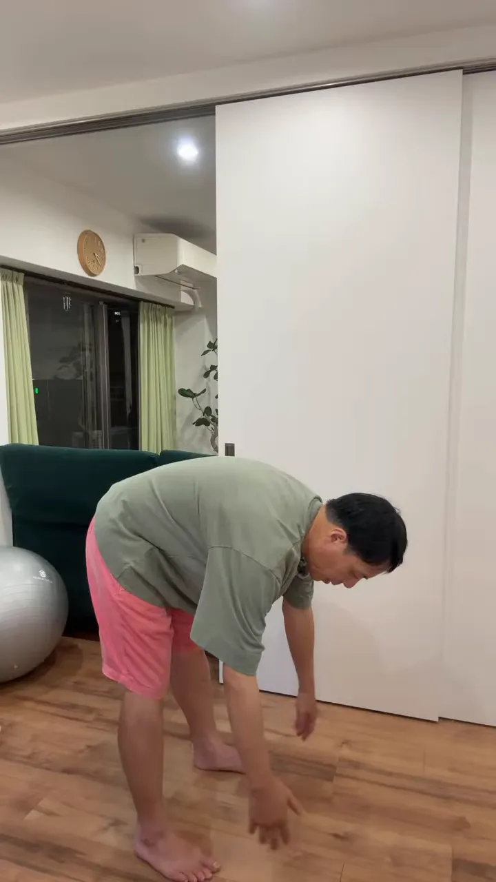 足を開いて立ち、両腕を下ろして前屈している姿