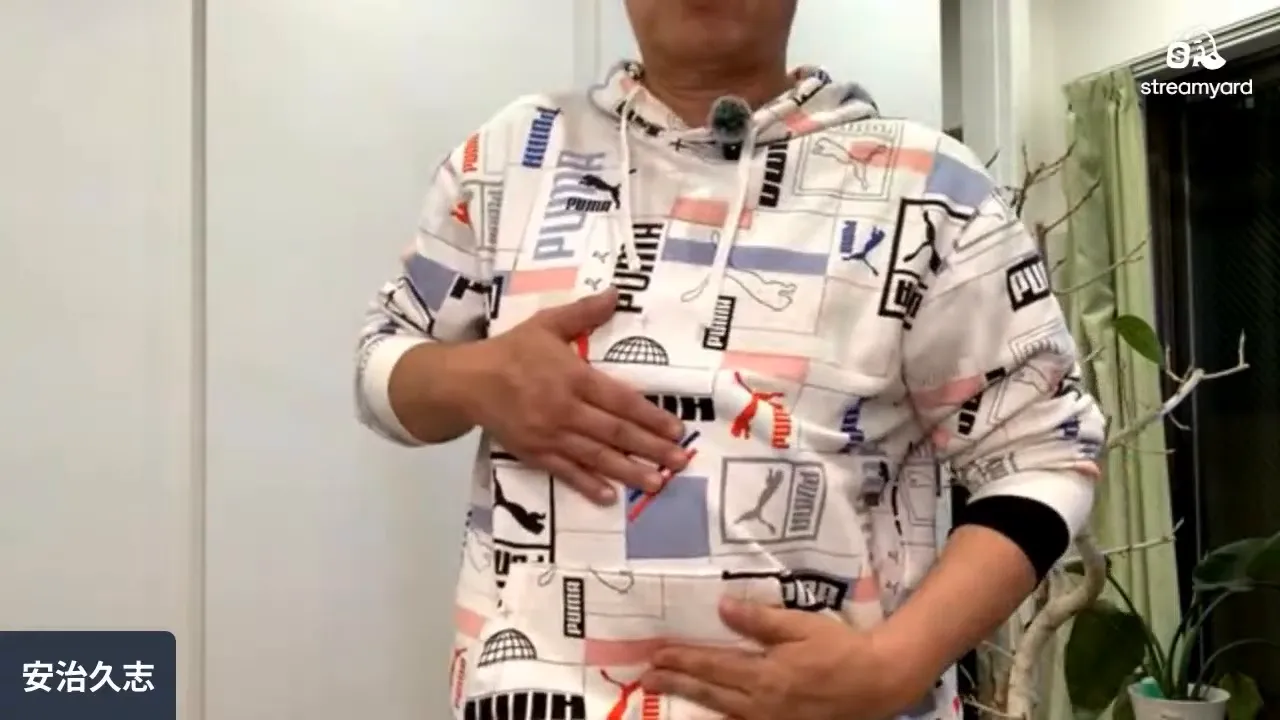 男性がみぞおちとおへその間に両手を当てている