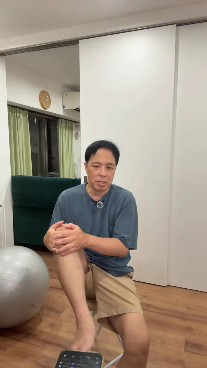 椅子に座った男性が片膝を抱え、足を浮かせて足首を動かしている