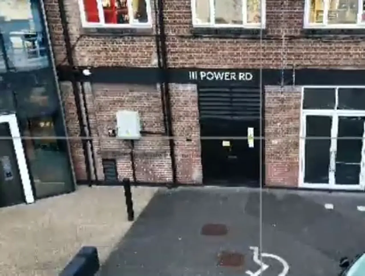 Straight-on drone frame of a brick building facade and entrance showing clear overlap and ground markers.