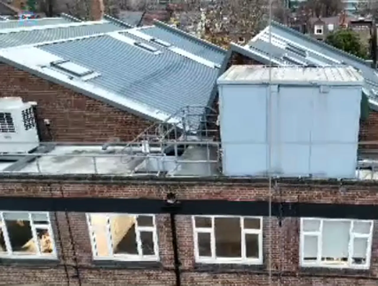 clear drone view of brick building facade with rooftop equipment and windows