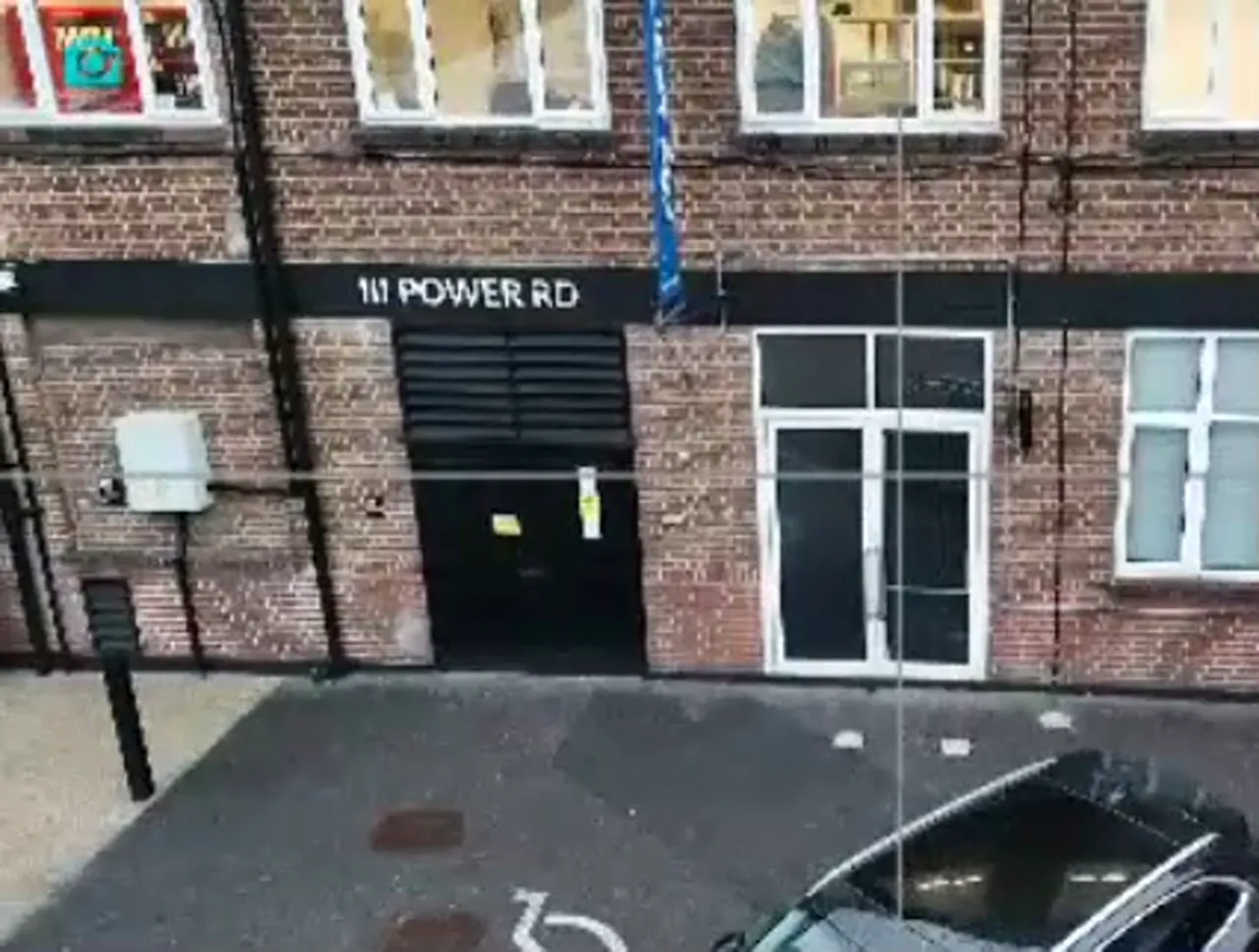 wide drone shot of brick facade, entrance and street showing urban canyon effect