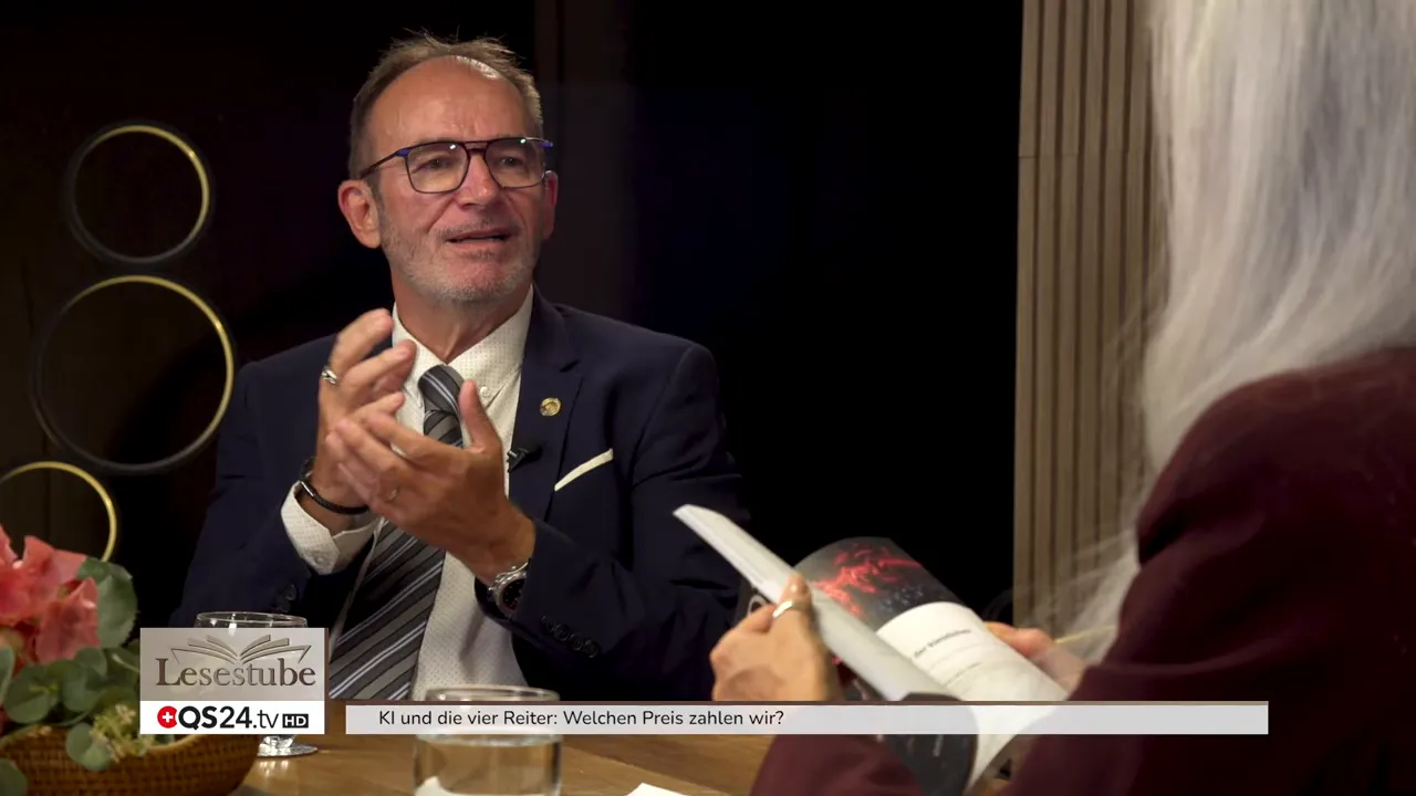 Alexandra Wurlitzer hält ein aufgeschlagenes Buch im Vordergrund, ihr Gast sitzt gegenüber