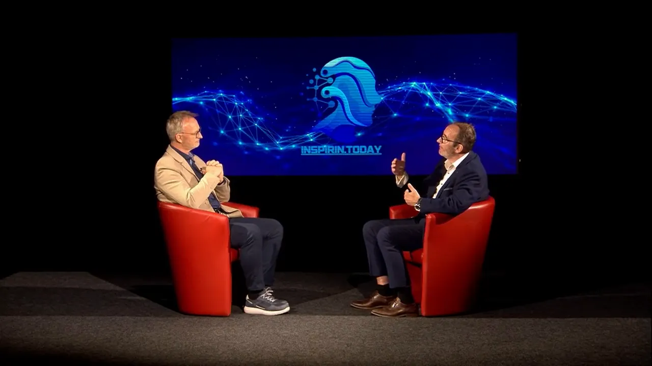 Zwei Gesprächspartner in roten Sesseln vor großem Bildschirm mit Inspirin.Today‑Logo und digitaler Netzwerkgrafik.